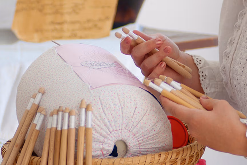 Hands holding bobbins and making lepoglava lace