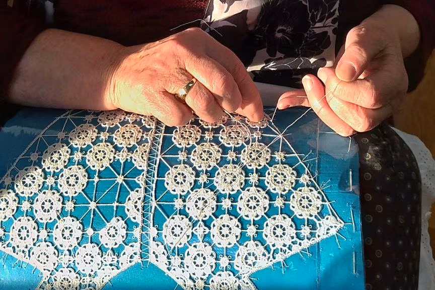Hands holdings needle and making Pag lace