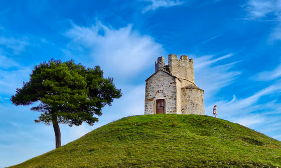Church, women, and tree, on top of a hill